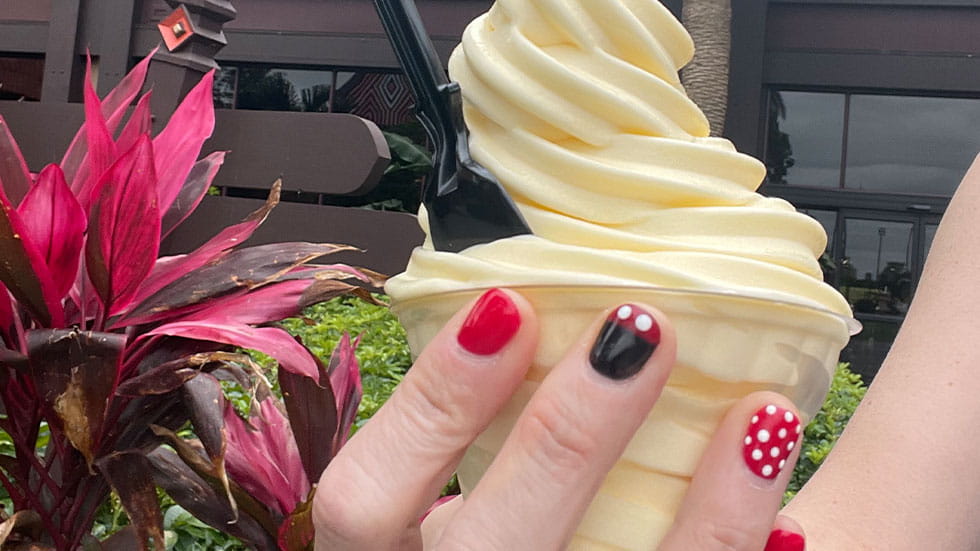 Woman holding ice cream cone with Disney themed nail art on fingernails