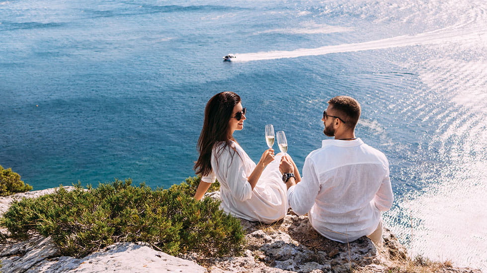 A couple in love drinking champagne on the seashore. Photo courtesy of Mikhail Sotnikov/iStock.com