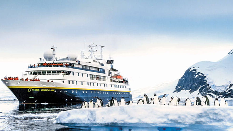 penguins on an iceberg in front of Lindblad cruise ship