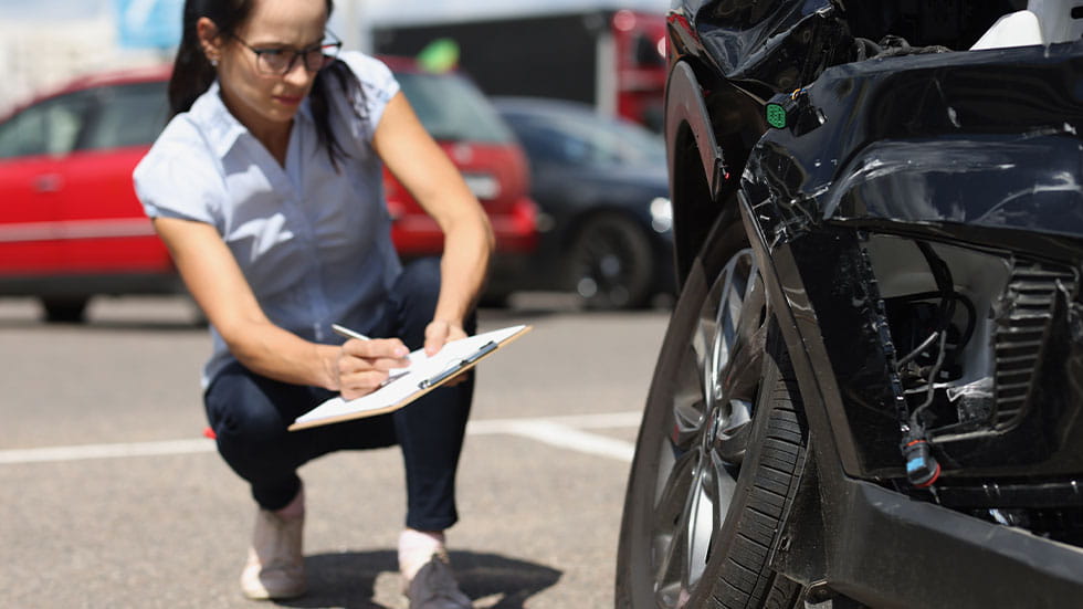 woman writing down car damages on a clipboard