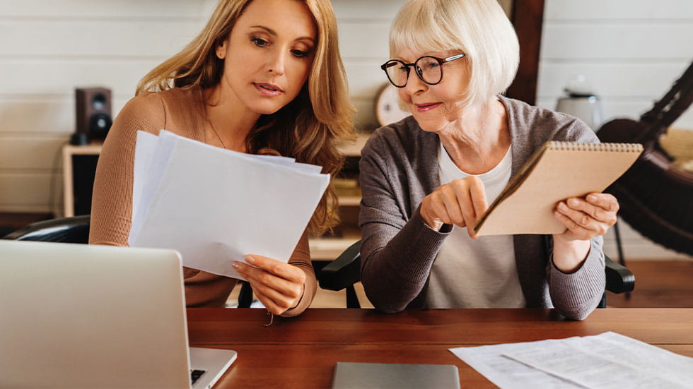 Younger woman and elder woman looking at documents and laptop