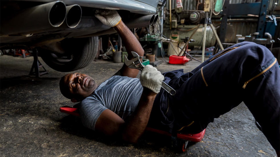 Car mechanic doing work underneath a car