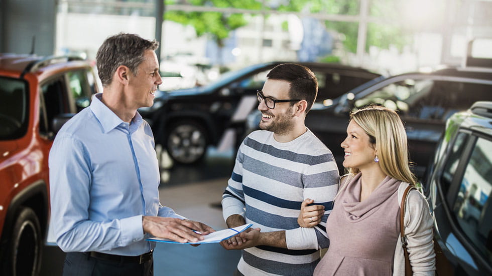 Pregnant couple talking to car salesperson