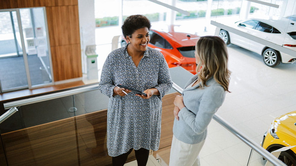woman speaking to car salesperson at car dealership