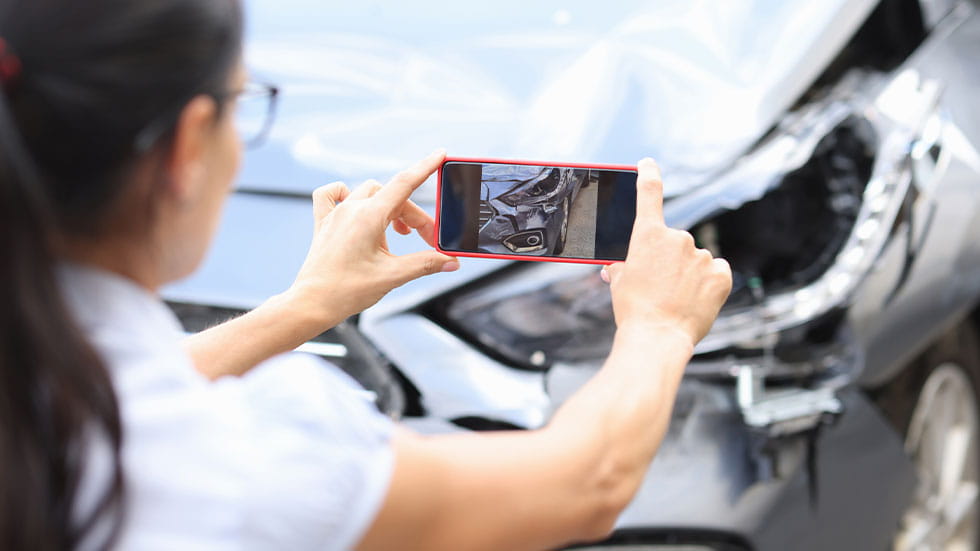 woman taking picture of damaged car