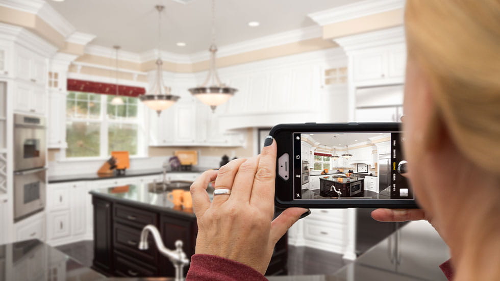 woman taking picture of kitchen on phone