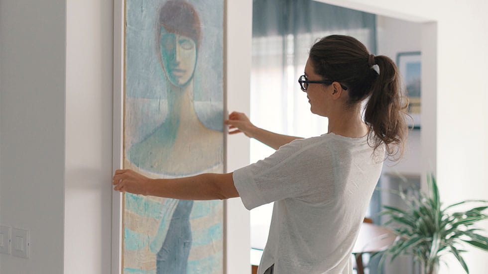 woman hinging painting on wall