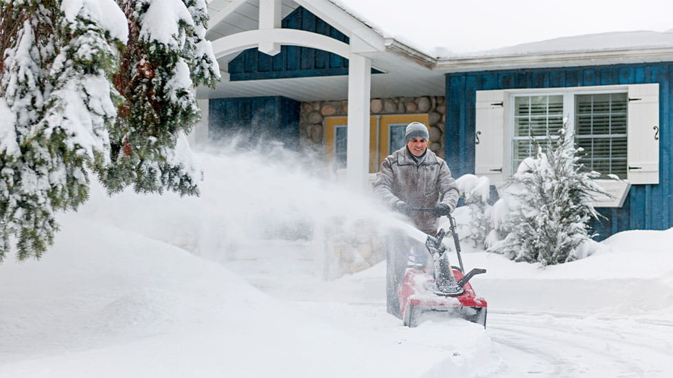 man using snow blower on driveway