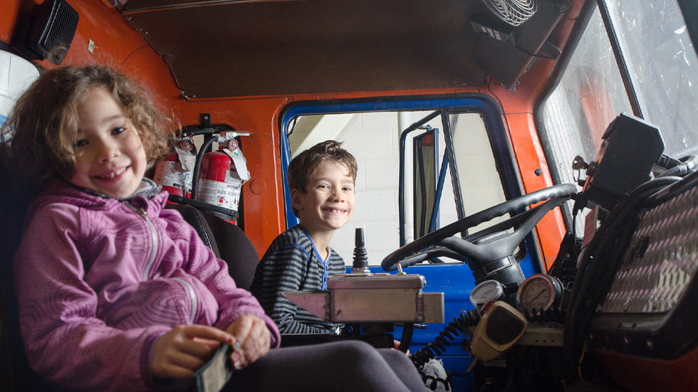 Little boy and girl sitting in a firetruck and smiling