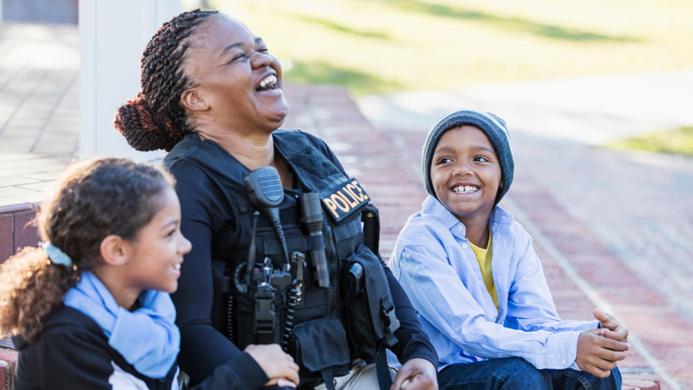 Police officer sitting with two children, laughing