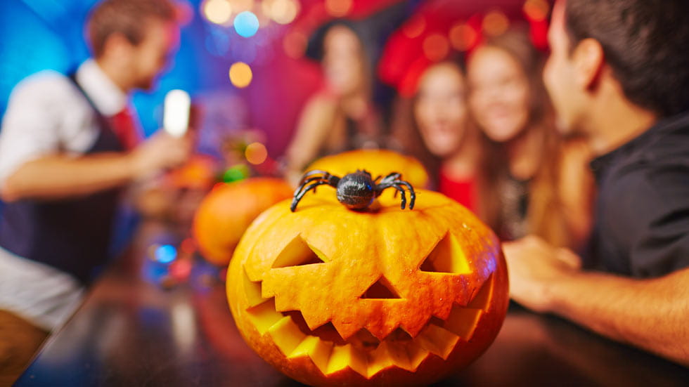 Pumpkin and spider sitting on a bar with people in background