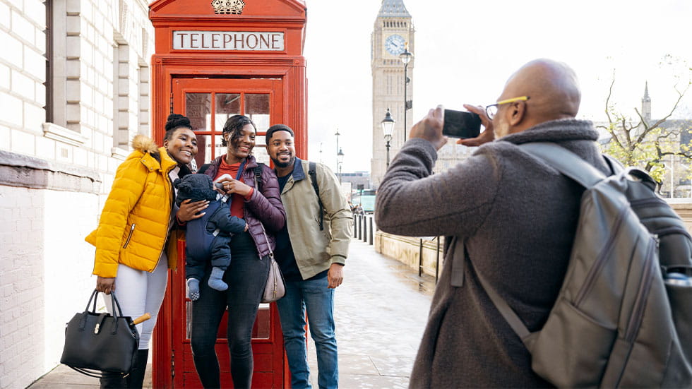 family taking photo in front of London phone booth with Big Ben in the background