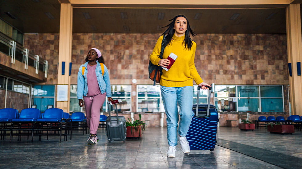 Two women in airport carrying suitcases