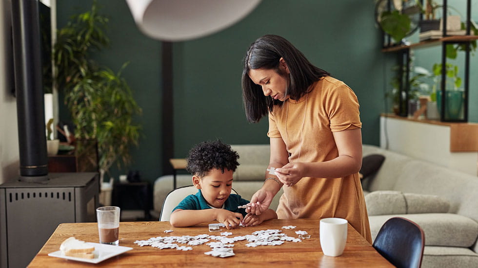 Shot of an adorable little boy completing a puzzle with his mother at home