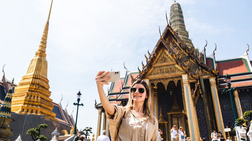 Woman taking a selfie in front of The Grand Palace in Bangkok