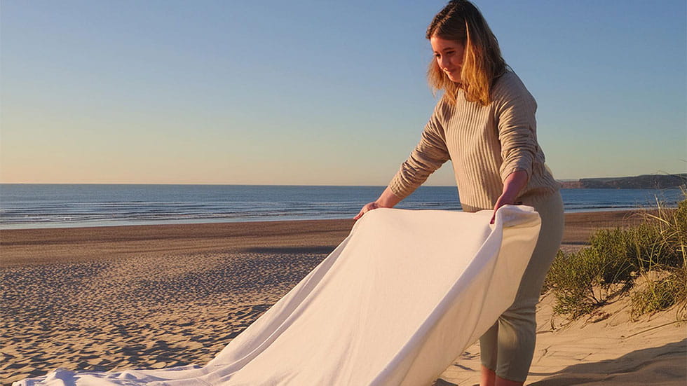 woman spreading blanket on beach