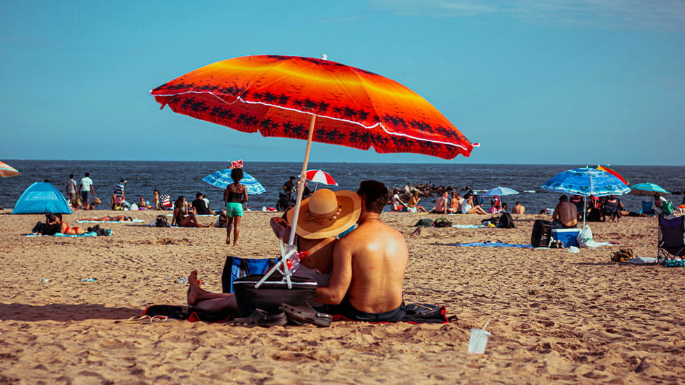 man and woman under a bright umbrella on the beach
