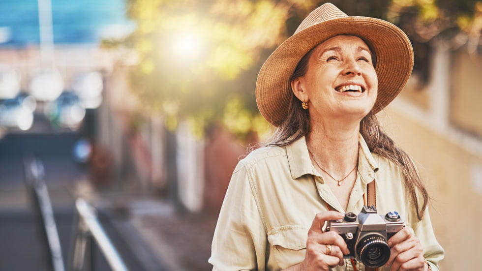 Woman wearing a straw hat while holding a camera