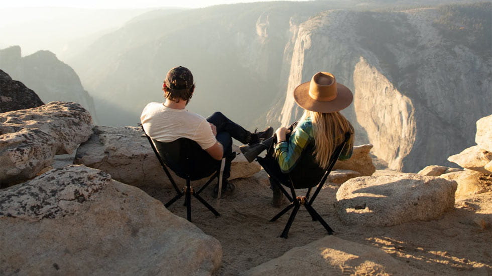 Couple sitting on top of mountain looking out towards view