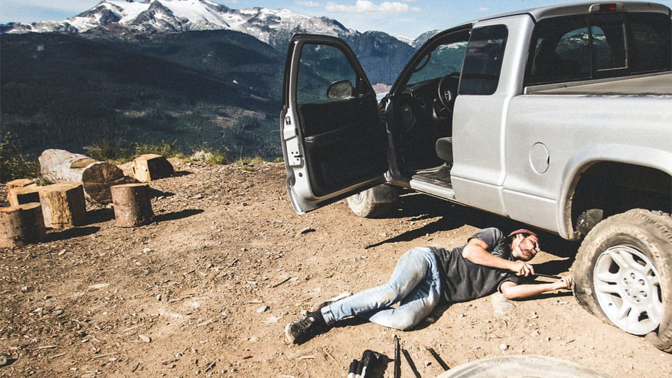 Man laying beside a truck changing it's tire