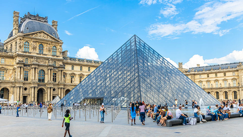 Tourists outside the glass Pyramid at the entrance of the Louvre Museum.  Phto by Jean-Luc Ichard/iStock.com