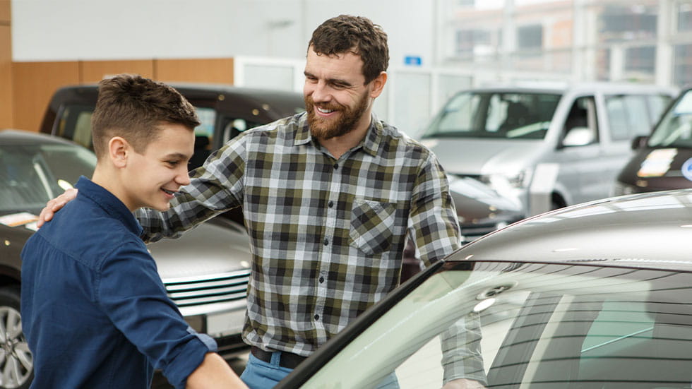 Father and teenage son buying car