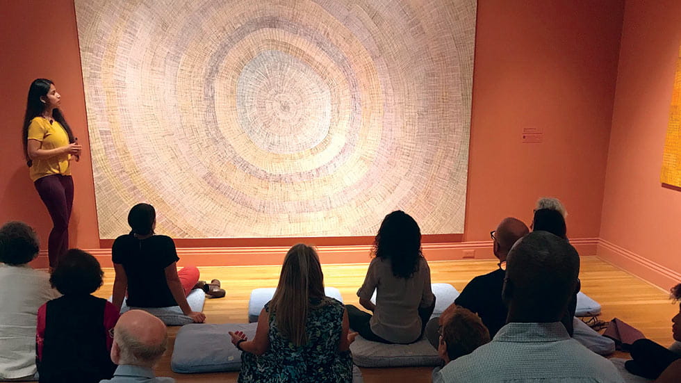 Group meditating in front of Regina Pilawuk Wilson's Sun Matt (2015)