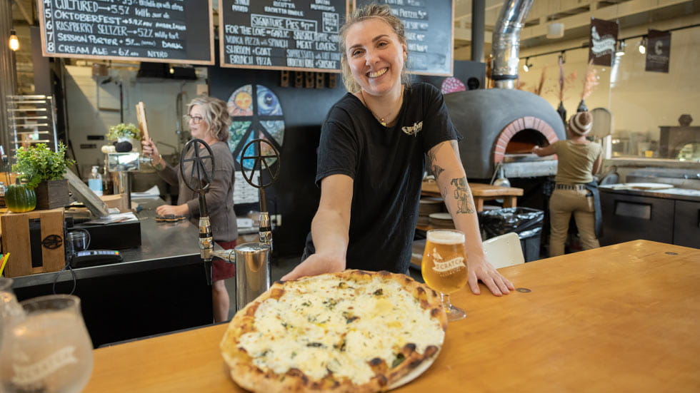 Woman serving pizza at a food hall