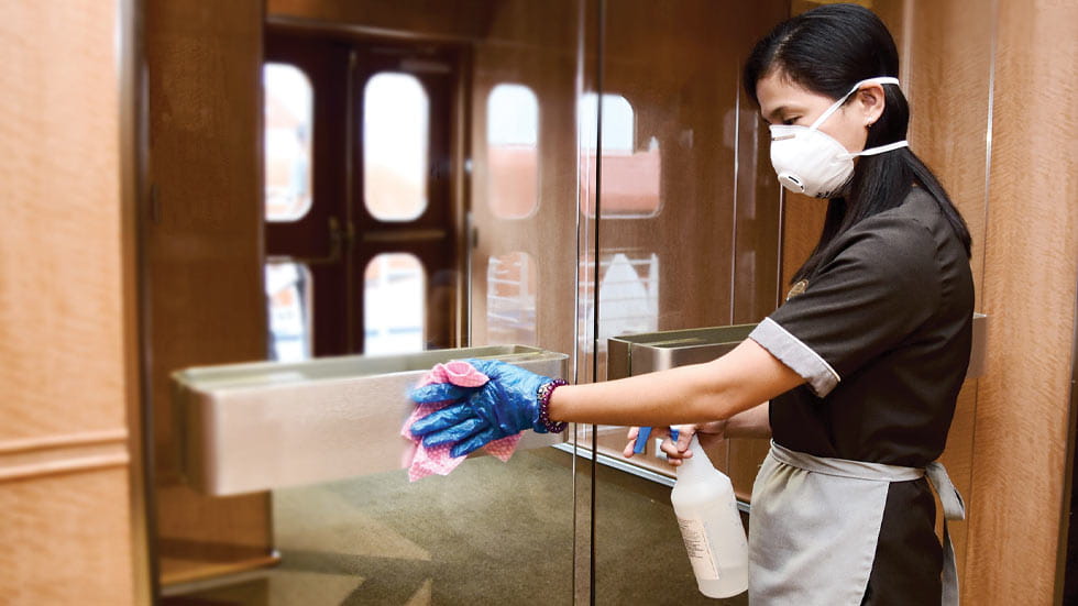 Woman cleaning glass doors on cruise ship