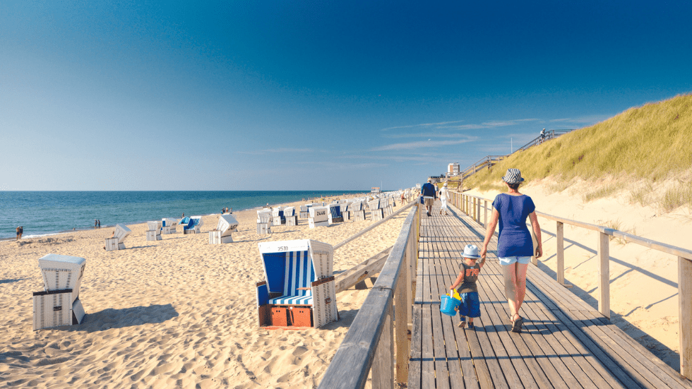 A boardwalk follows the beach of the North Sea coast and its straw beach chairs on the island of Sylt