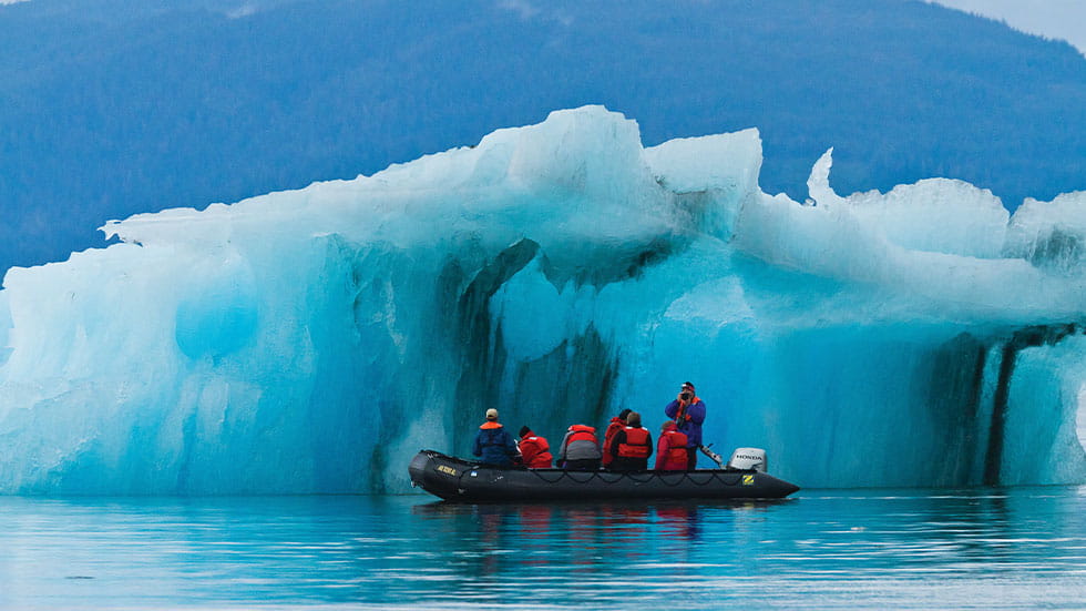 Zodiac boat pulling in close beside glacial ice