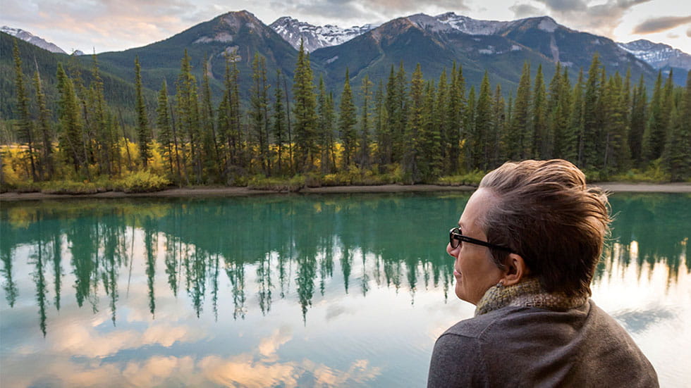 woman looking out at lake with mountains in background