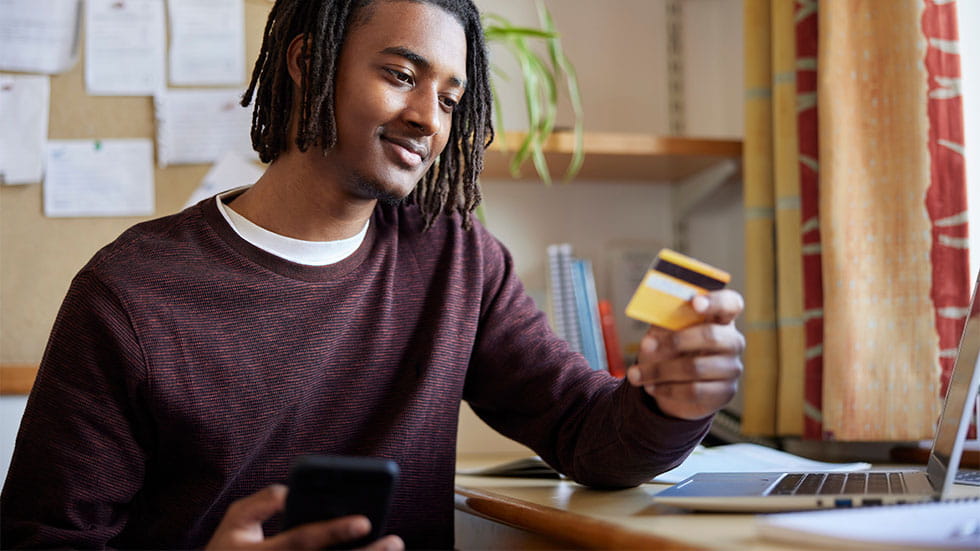 boy looking at debit card and holding phone
