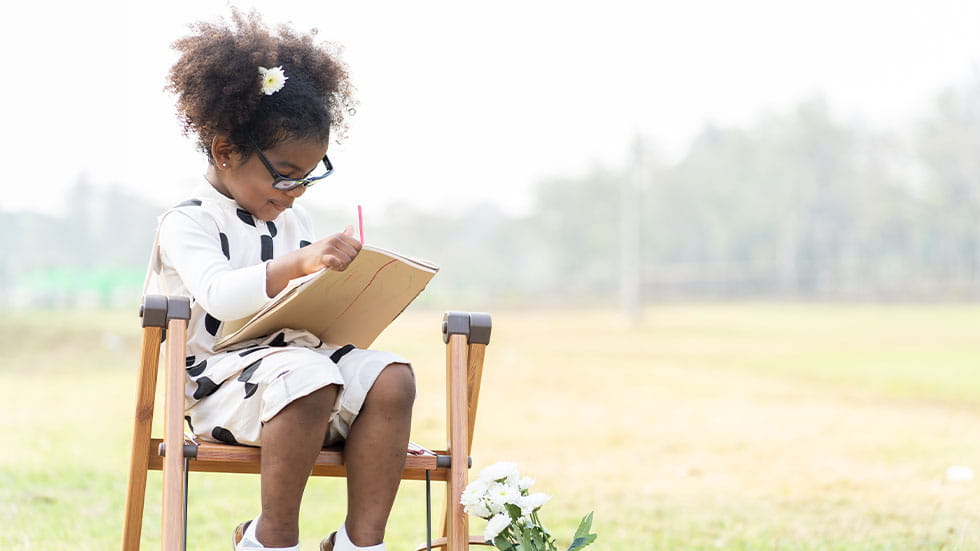 little girl wearing glasses reading a book