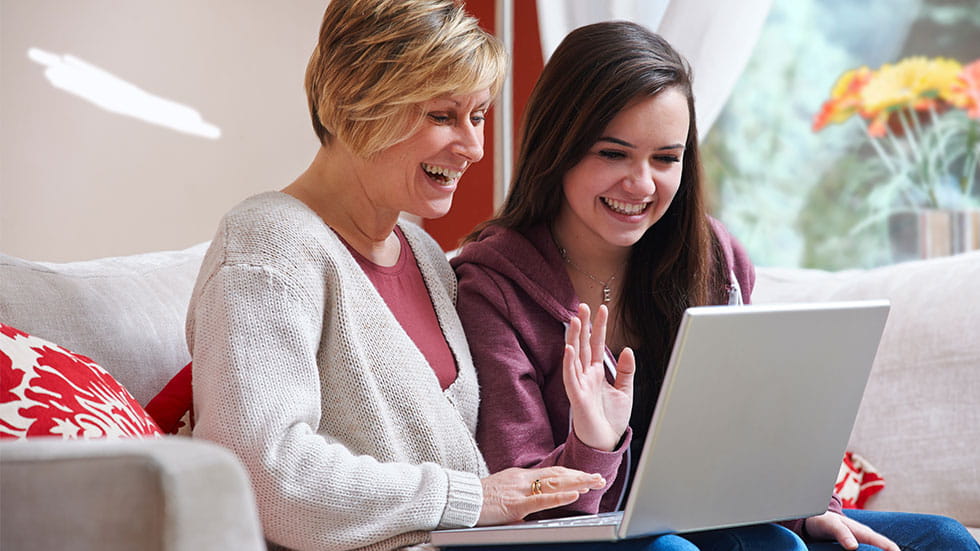 Mother and daughter smiling at laptop screen