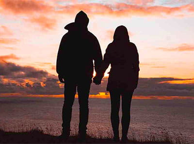 Silhouette of couple standing watching sunset