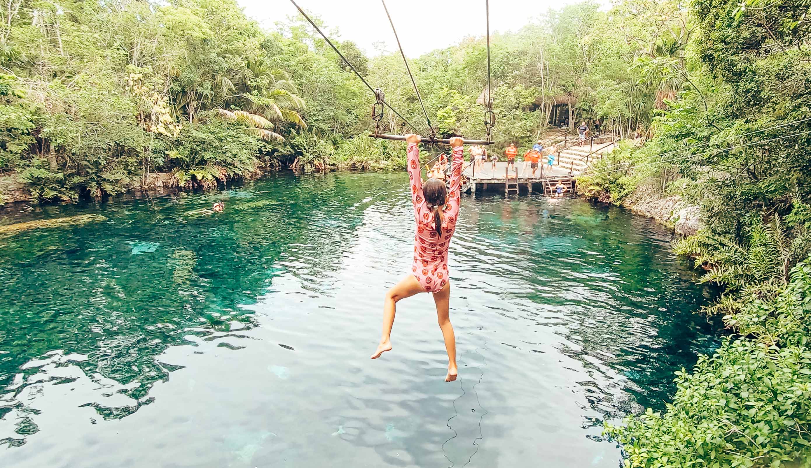 Young girl riding a zipline over water in Mexico