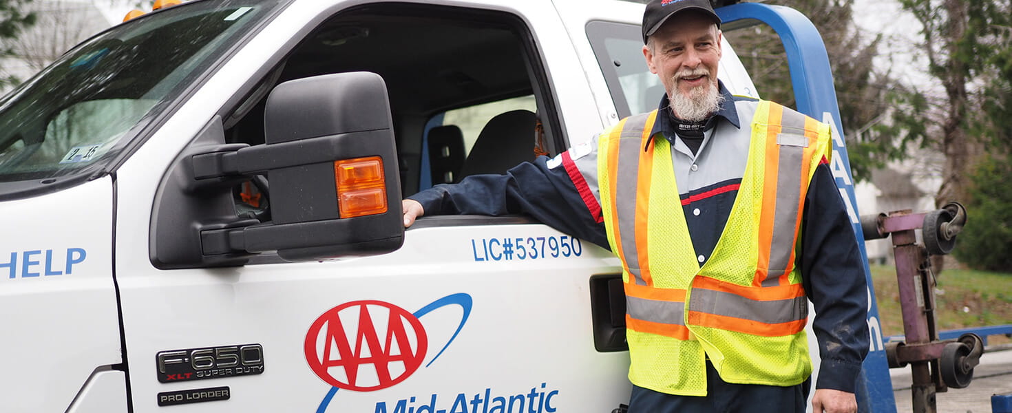 A real-ilfe AAA tow truck driver stands by his AAA tow truck ready to be of service.